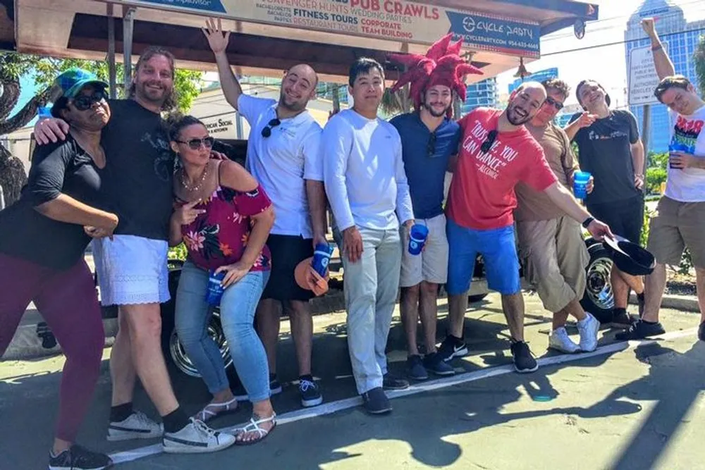 A group of cheerful people posing for a photo with some holding drinks and making playful gestures possibly before or after participating in a social event like a pub crawl