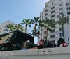A group of passengers enjoys a sunny sightseeing tour on an open-top bus labeled Open Miami surrounded by palm trees