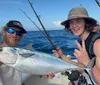 Two individuals are posing with a large fish on a boat showcasing their catch with cheerful expressions