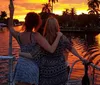 Five smiling women pose closely together for a photograph with a blurry sunset and city skyline in the background suggesting they are enjoying a social outing