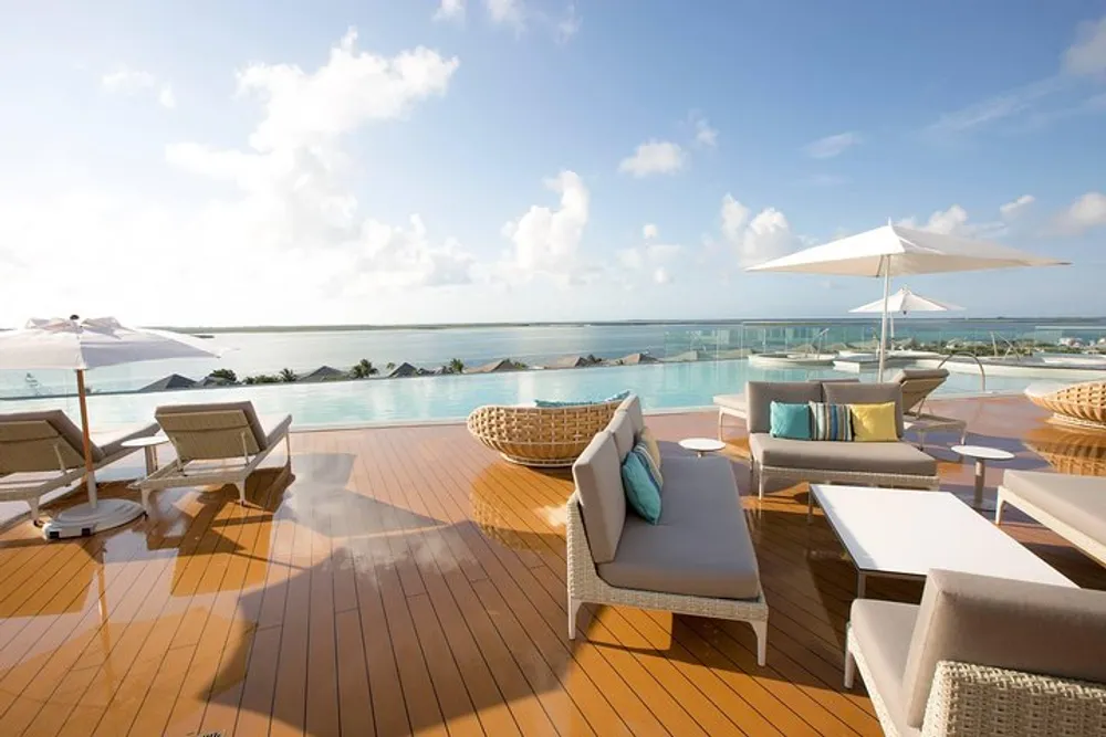 An elegant outdoor deck features modern furniture a sun umbrella with a stunning view of the sea and the sky
