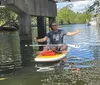 Three people are stand-up paddleboarding in a sunny waterway with boats and waterfront homes in the background