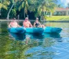 Three individuals are enjoying their time on a kayak in a scenic waterway surrounded by palm trees and waterfront properties