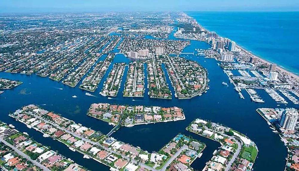 This is an aerial view of a coastal urban area featuring numerous canals and waterways with residential and commercial buildings closely packed along their banks leading out to a larger body of water