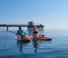 A person is paddleboarding on a calm sea with a view of a coastal city skyline in the background