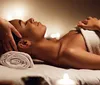 The image depicts a serene scene of a person receiving a head massage in a candlelit setting suggesting a relaxed and soothing spa experience