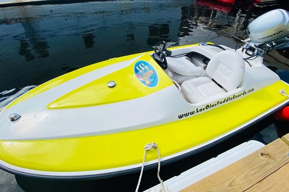 The image shows a bright yellow and white motorized paddle boat tied to a dock with water in the background