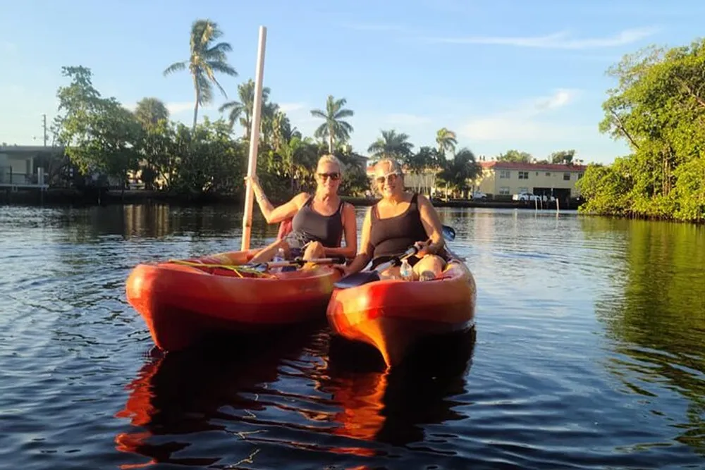 Two people are sitting in separate kayaks enjoying a sunny day on the water with tropical surroundings