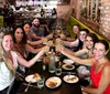 A group of smiling people is toasting at a restaurant table sharing a meal together