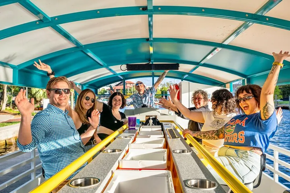 A group of cheerful people are waving and enjoying themselves on a boat with a blue and white canopy