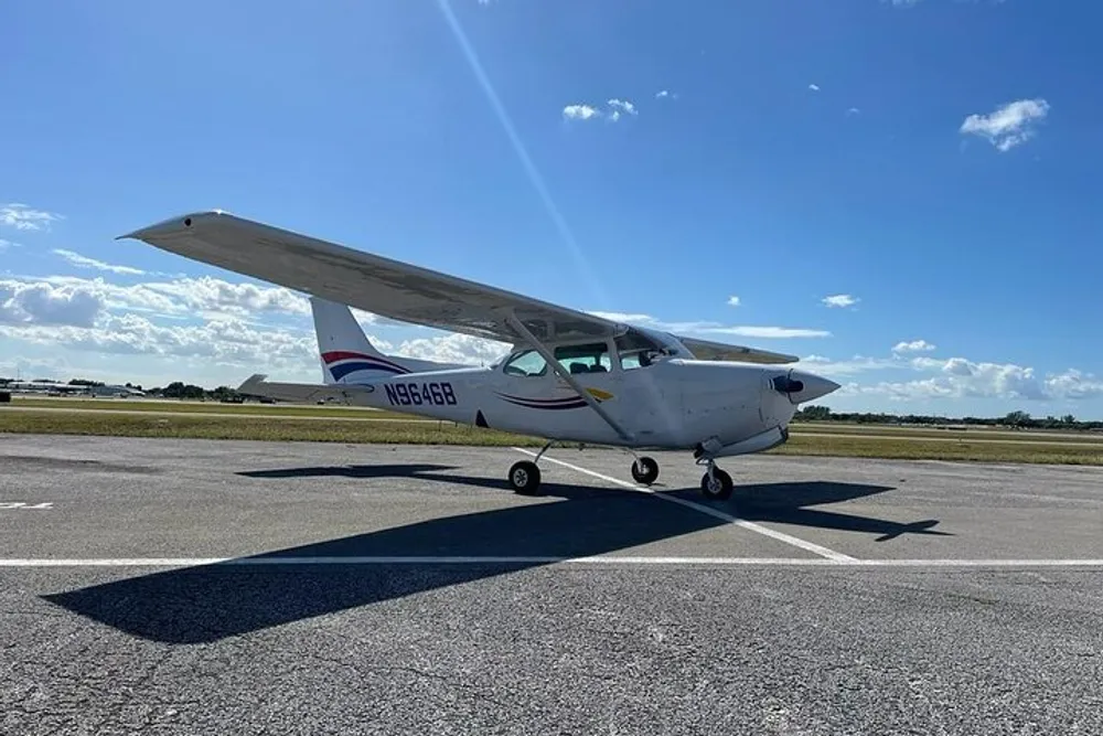 A single-engine light aircraft is parked on a runway under a clear blue sky