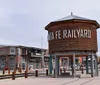 The image shows the Santa Fe Railyard area with a large vintage wooden water tower featuring the text Santa Fe Railyard in a modernized urban setting with clear skies overhead
