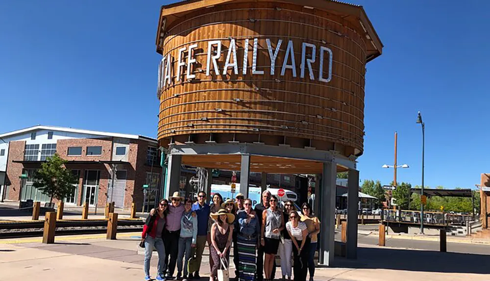 A group of people is posing for a photo in front of a rustic-looking entrance with the words THE RAILYARD in Santa Fe New Mexico