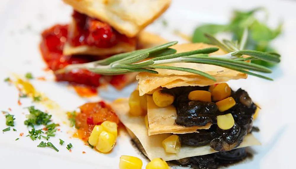 A gourmet dish with layered pastry mushrooms corn and herbs artistically presented on a white plate