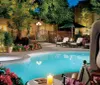 An elegant outdoor pool area is adorned with lush plants flowers and a large sculpture creating a serene evening atmosphere