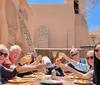A group of smiling people are toasting with drinks at an outdoor dining table under a clear blue sky