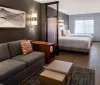 The image displays a modern hotel suite with a separate living area and bedroom characterized by contemporary furniture warm lighting and tasteful decor