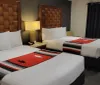 The image shows a neatly arranged hotel room with two beds adorned with decorative blankets featuring what appears to be a southwestern or Native American design