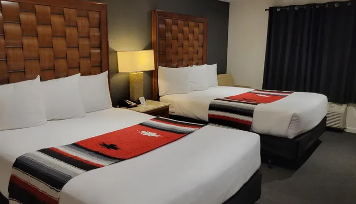 The image shows a neatly arranged hotel room with two beds adorned with decorative blankets featuring what appears to be a southwestern or Native American design