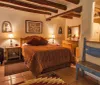 The image shows a cozy southwestern-styled room with terracotta floor tiles a rustic wooden beam ceiling and culturally-inspired decor and textiles