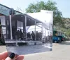 A persons hand is holding up a black and white photo of an old post office blending the past scene with the current street view in color