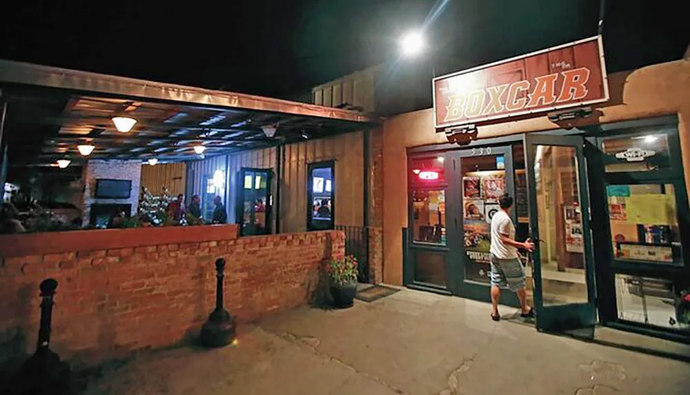 The image shows a person entering a bar called BOXCAR at night with people visible inside and an adjacent covered patio area