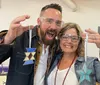 A man and a woman are smiling and posing with star-shaped glass art pieces wearing protective eyewear likely inside a workshop