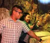 A man and a woman appear to be enjoying an interactive exhibit with rock-like textures and tribal artifacts in the background