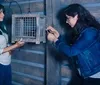 Two women are solving a puzzle involving a cage or box in what appears to be an escape room or interactive game setting