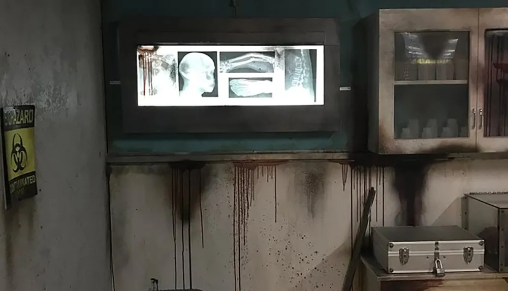 The image depicts a grim dimly lit room resembling a laboratory or medical facility with a biohazard warning x-ray lightbox displaying medical images and signs of neglect or decay