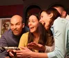 Four people are excitedly gathered around a mysterious vintage-looking device with expressions ranging from amazement to amusement