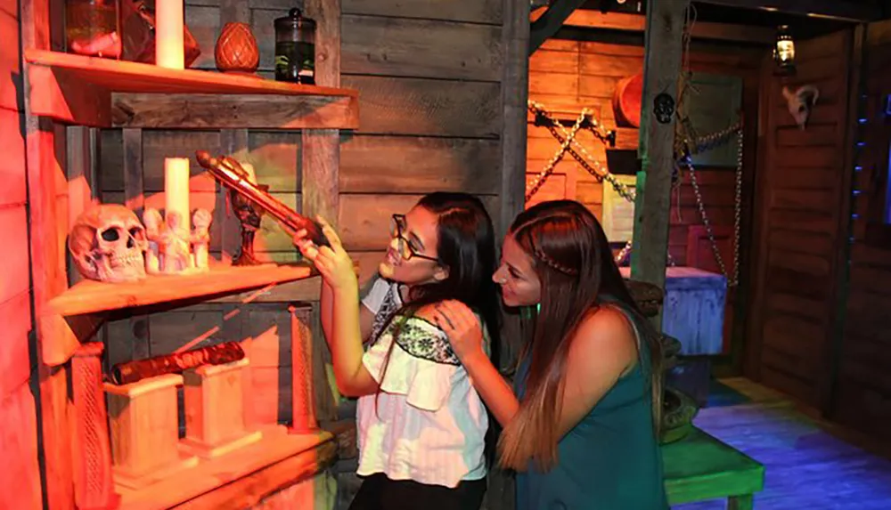 Two women are examining a magic wand in a room decorated with whimsical and mystical items creating an atmosphere reminiscent of a wizards den