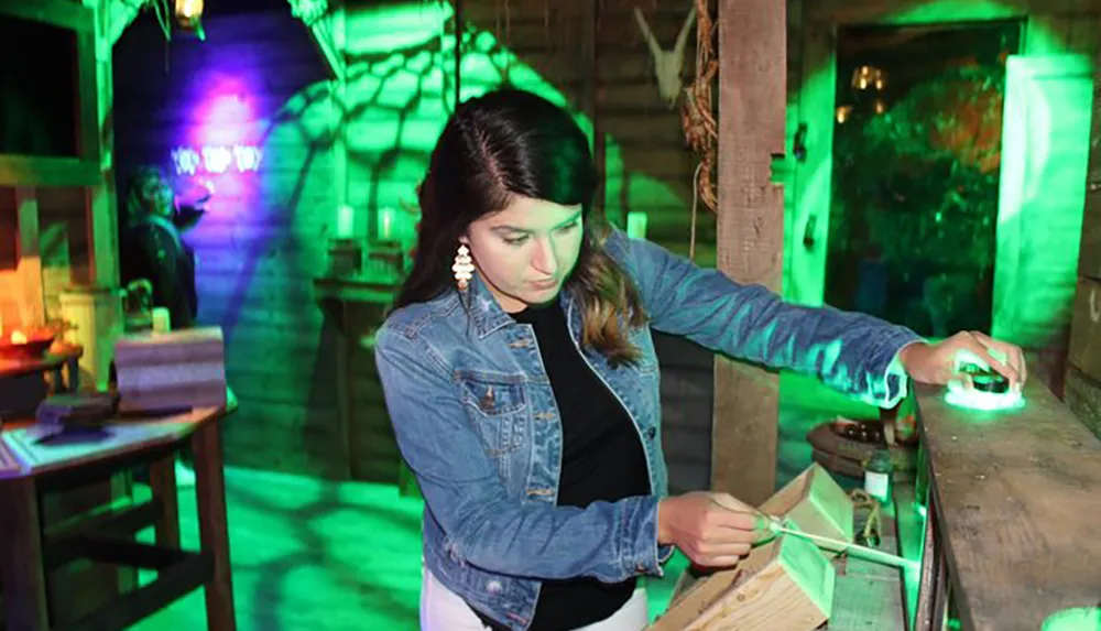 A woman is engaged in an interactive exhibit illuminated by green and purple lighting creating an eerie atmosphere