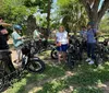 A group of people on electric bikes are posing for a photo in front of an old church with two bell towers