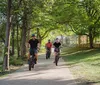 Three individuals are cycling along a path with a cityscape in the background