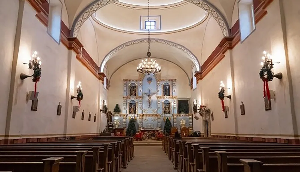 The image shows the interior of a church with rows of pews an ornate altar and walls adorned with Christmas wreaths suggesting it might be decorated for a holiday season