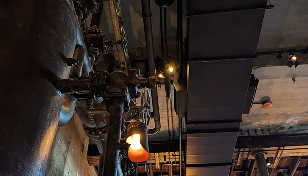 The image shows a dimly lit industrial-themed room with exposed pipes and hanging lights creating a rustic atmosphere