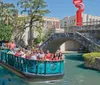 This is an advertisement for the San Antonio CityPASS featuring a vibrant scene of the River Walk with outdoor dining colorful umbrellas and a display of the pass on a mobile phone