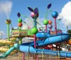 The image shows a colorful water park play structure with several slides and water-spraying features that resemble whimsical flowers