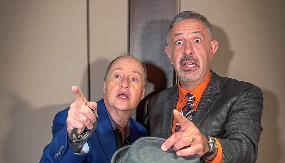 Two men are making surprised expressions and pointing towards something off-camera with one of them handcuffed creating a humorous and intriguing scene