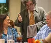 A group of people is enjoying a meal at a restaurant receiving positive reviews for the food and experience with a waiter giving a thumbs-up sign