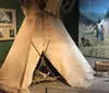 The image shows a museum exhibit featuring a tipi artifacts and informative displays about the Comanche and Kiowa peoples