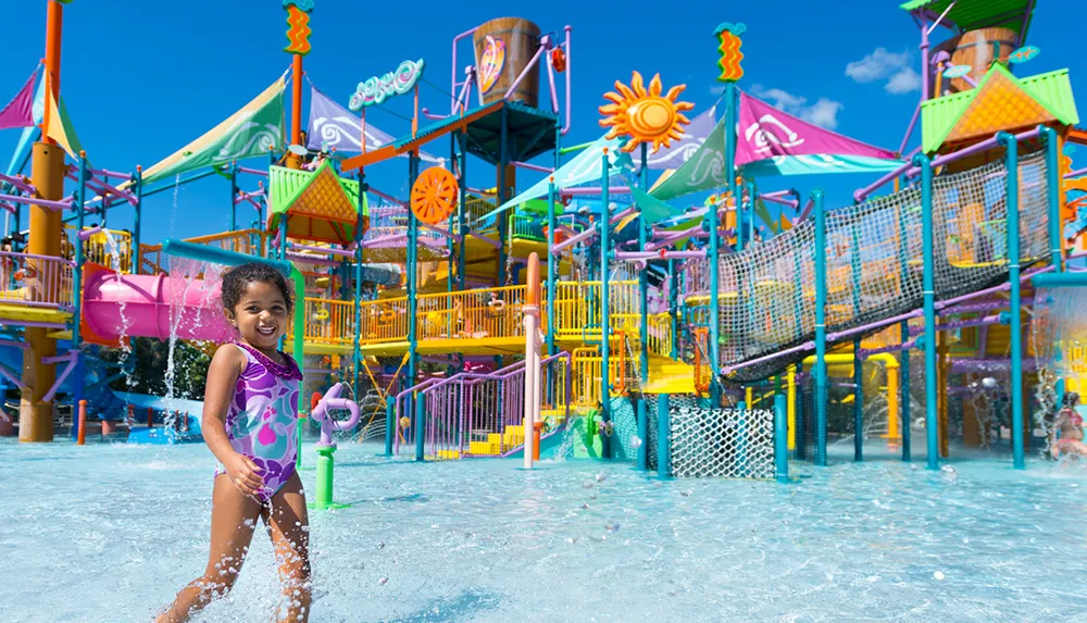 A joyful child is playing with a water toy in a colorful water park on a sunny day
