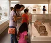 Visitors are closely examining ancient artifacts at a museum exhibit with a focus on a sarcophagus