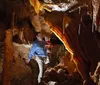 Three joyful individuals are posing with arms raised in a cave-like setting expressing happiness or excitement