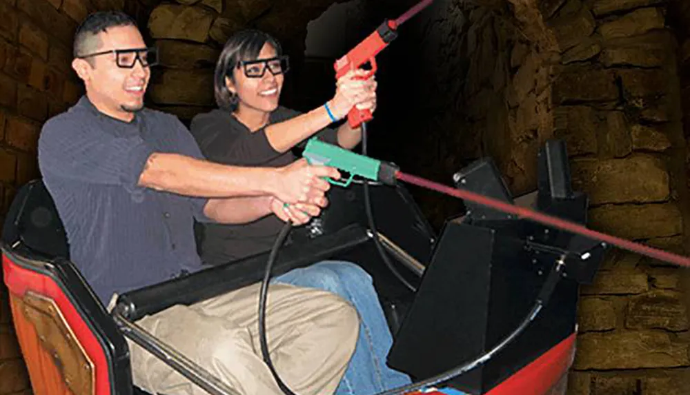 Two people wearing 3D glasses are enjoying a simulated shooting experience on a theme park ride