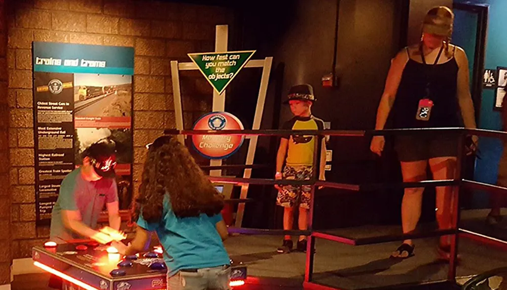 Two individuals are playing an air hockey game while another adult and child appear to be waiting for their turn or watching the game