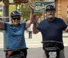 A group of people wearing helmets and riding Segways are waving cheerfully in front of a historic building