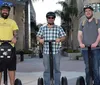 A group of people wearing helmets and riding Segways are waving cheerfully in front of a historic building