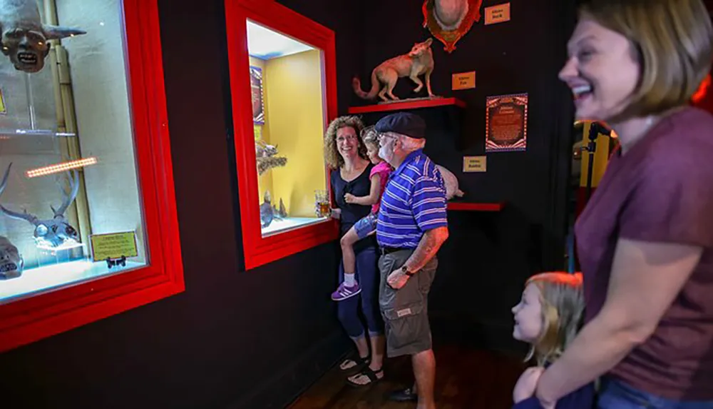 A family is enjoying their visit to a museum looking at various exhibits with a woman laughing and a child gazing at something with interest